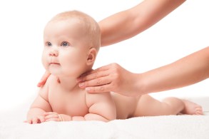 Cute baby lying. hands massaging his shoulders