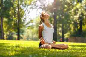 Young female doing yoga in nature on beautiful summer day