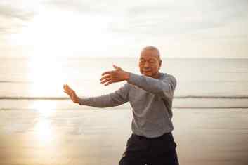 Asian Senior old man practice Tai chi and Yoga pose on the beach sunrise